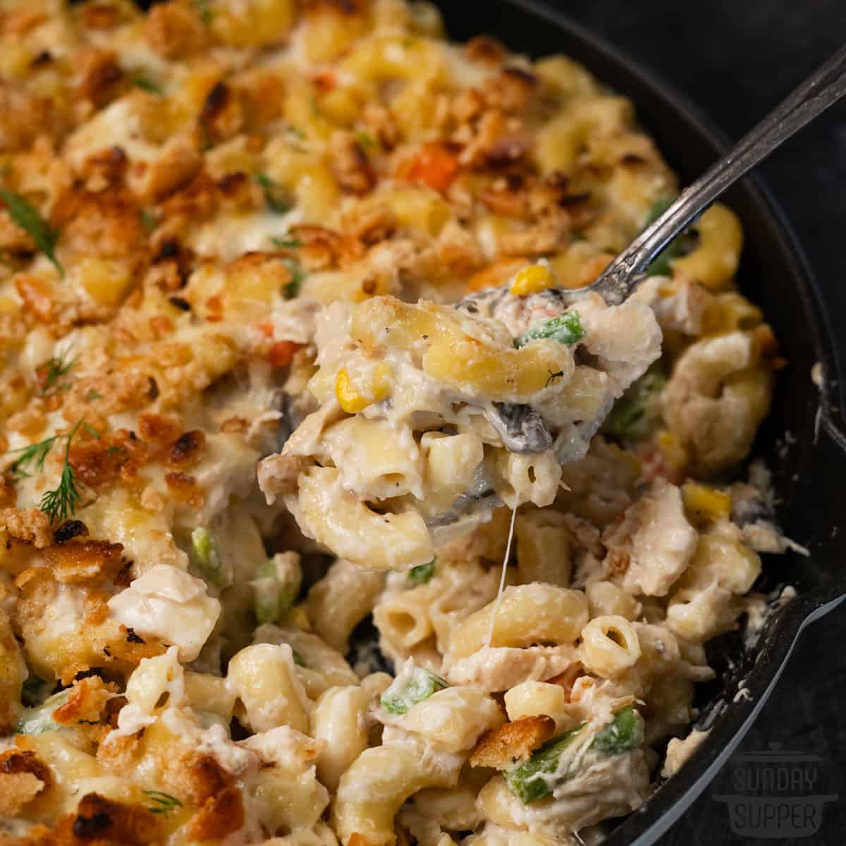 a spoon scooping tuna noodle casserole out of a pan