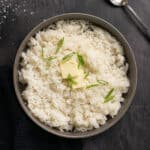 a bowl of white rice topped with extra butter and green onions