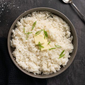a bowl of white rice topped with extra butter and green onions