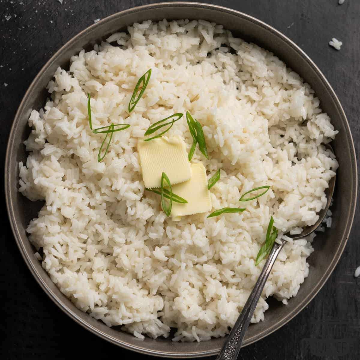 a bowl of fluffy white rice with extra butter and green onions