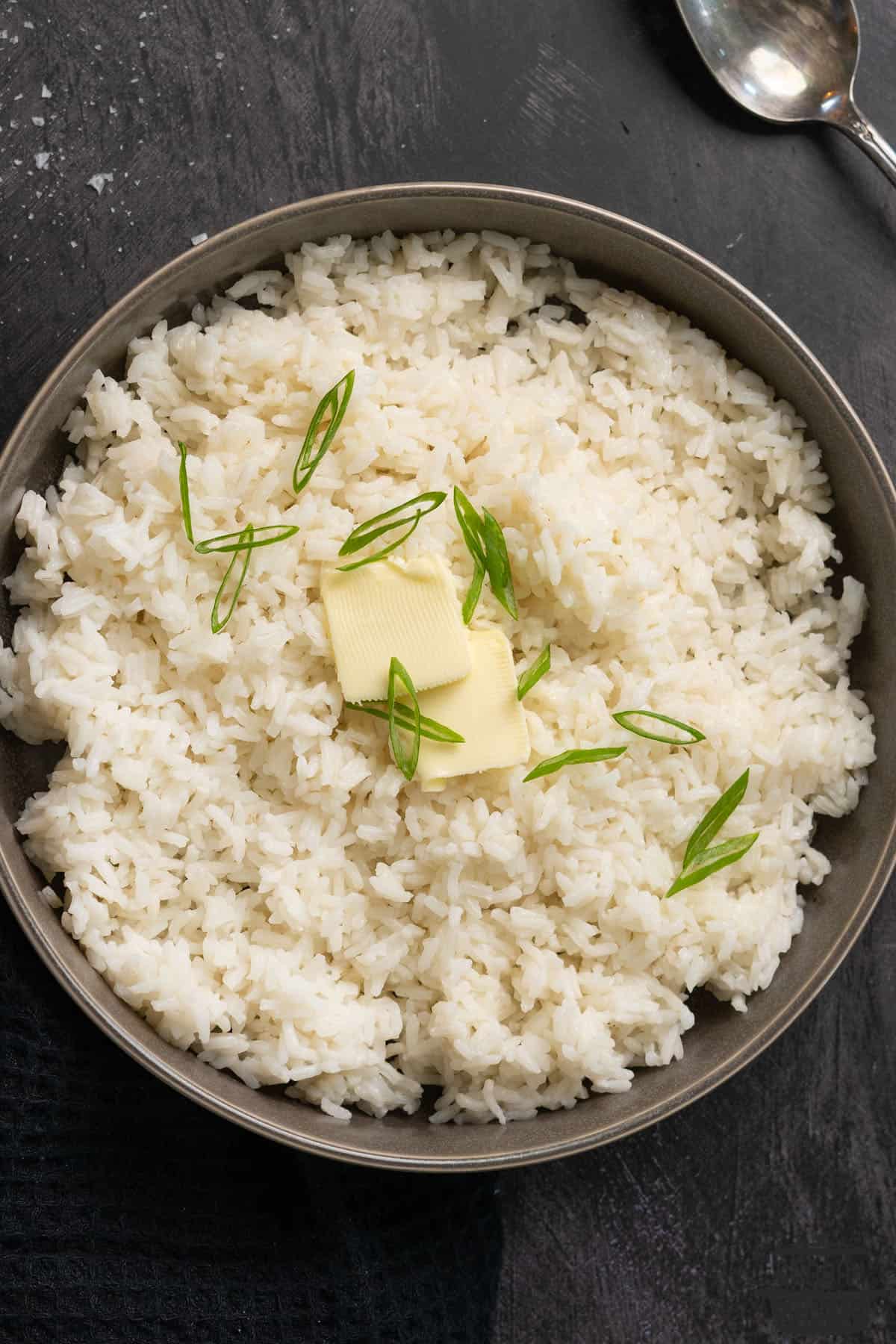 white rice in a bowl with butter and spring onions