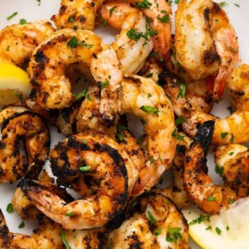 grilled shrimp on a plate with lemon wedges