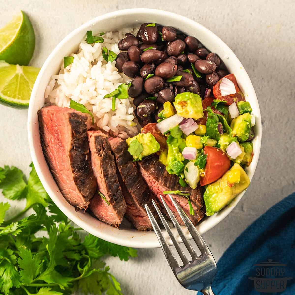 a rice bowl with flank steak, avocado salsa, and black beans