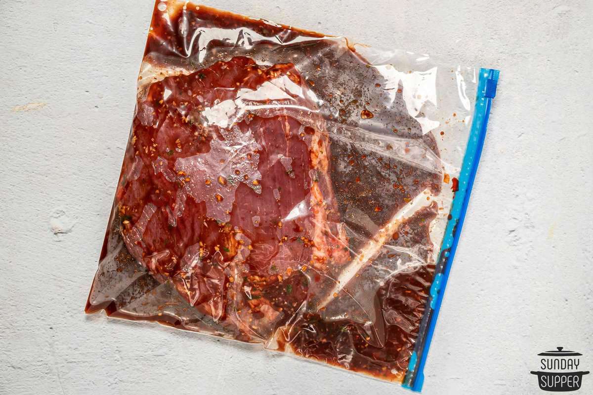 a steak in a ziplock bag with the marinade poured over it