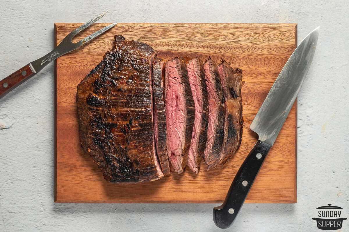 seared flank steak on a cutting board being sliced