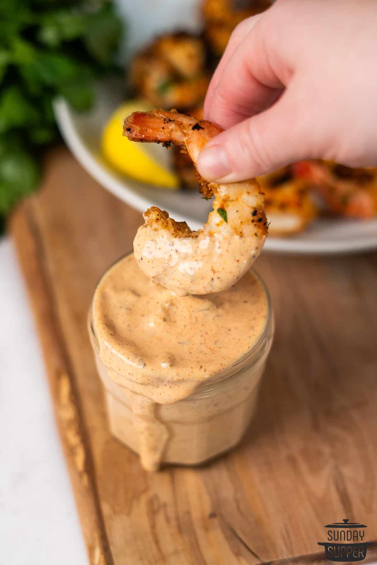 a grilled shrimp being dipped in remoulade sauce