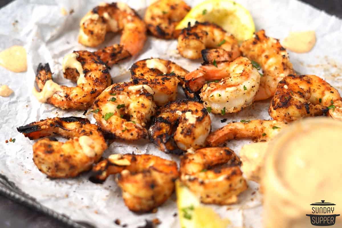 a baking sheet with lemon wedges and marinated grilled shrimp