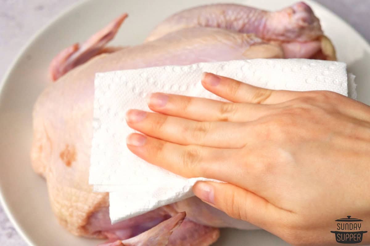 the raw chicken being pat dry