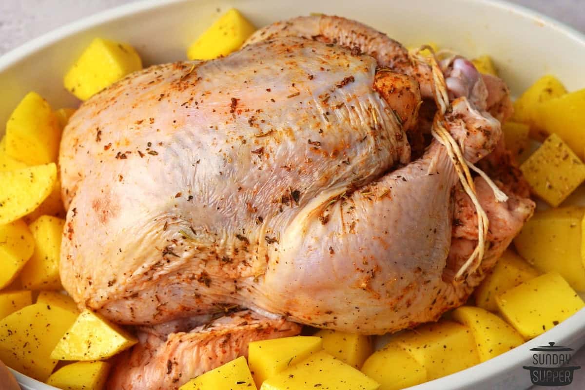 the chicken in a roasting pan with potatoes