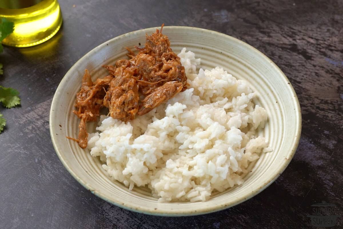 adding rice and pulled pork to a bowl