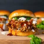 close up of pulled pork sandwich on a wood cutting board