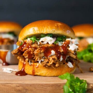 close up of pulled pork sandwich on a wood cutting board