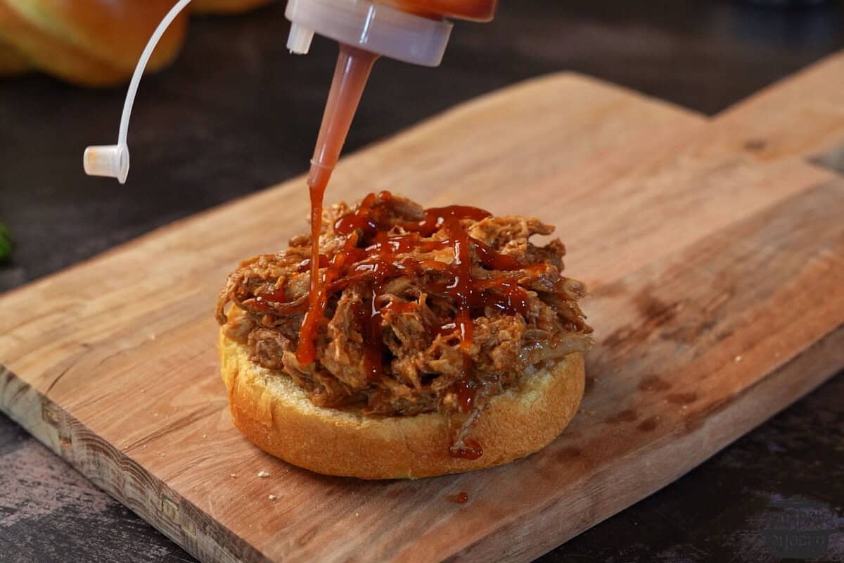adding bbq sauce to pulled pork