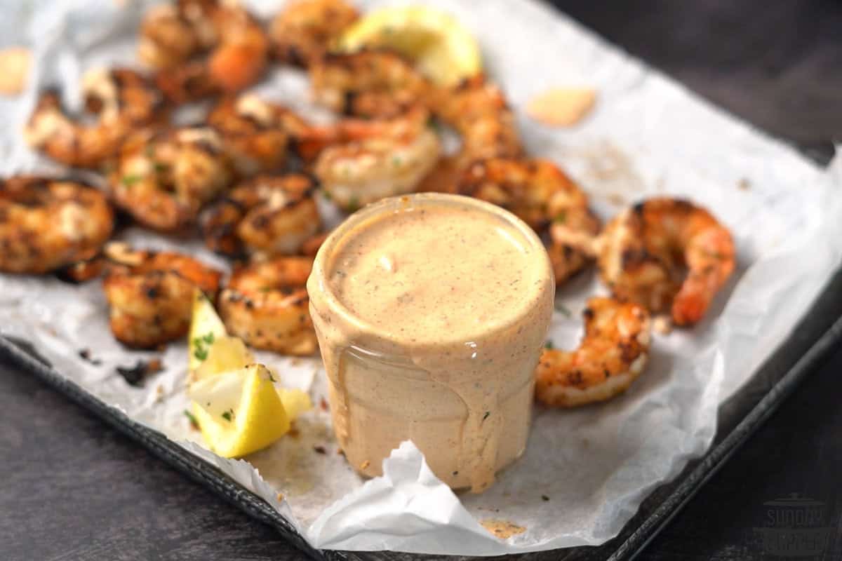 remoulade sauce in a clear jar with shrimp in the background