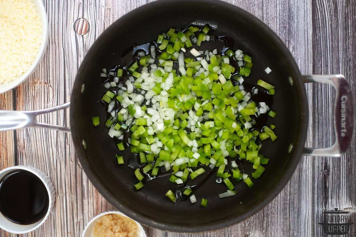 onions and green peppers sauteing in a pan with oil