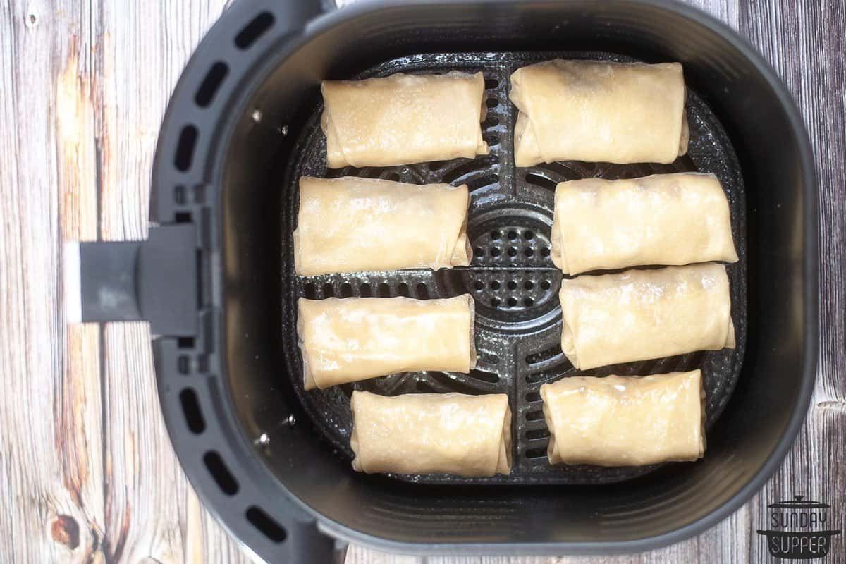 egg rolls placed in the air fryer after being brushed with oil
