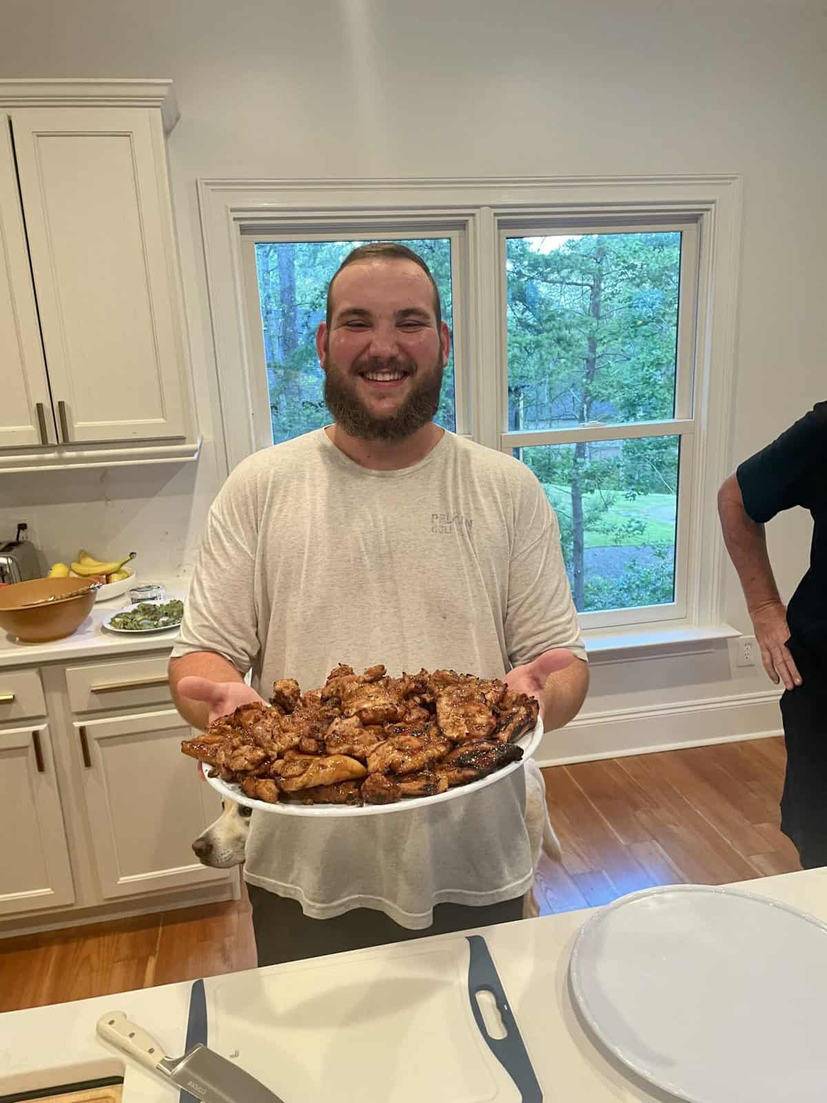 Reis holding grilled teriyaki chicken on a plate