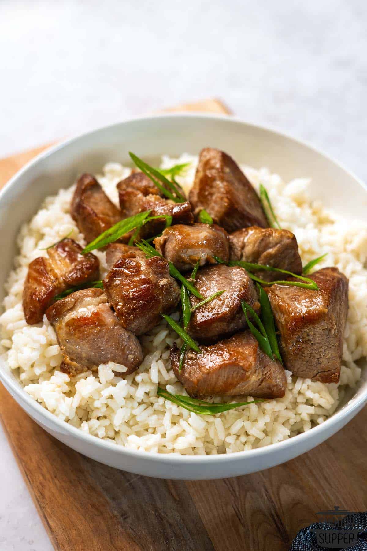 a bowl of rice topped with pork adobo and green onions