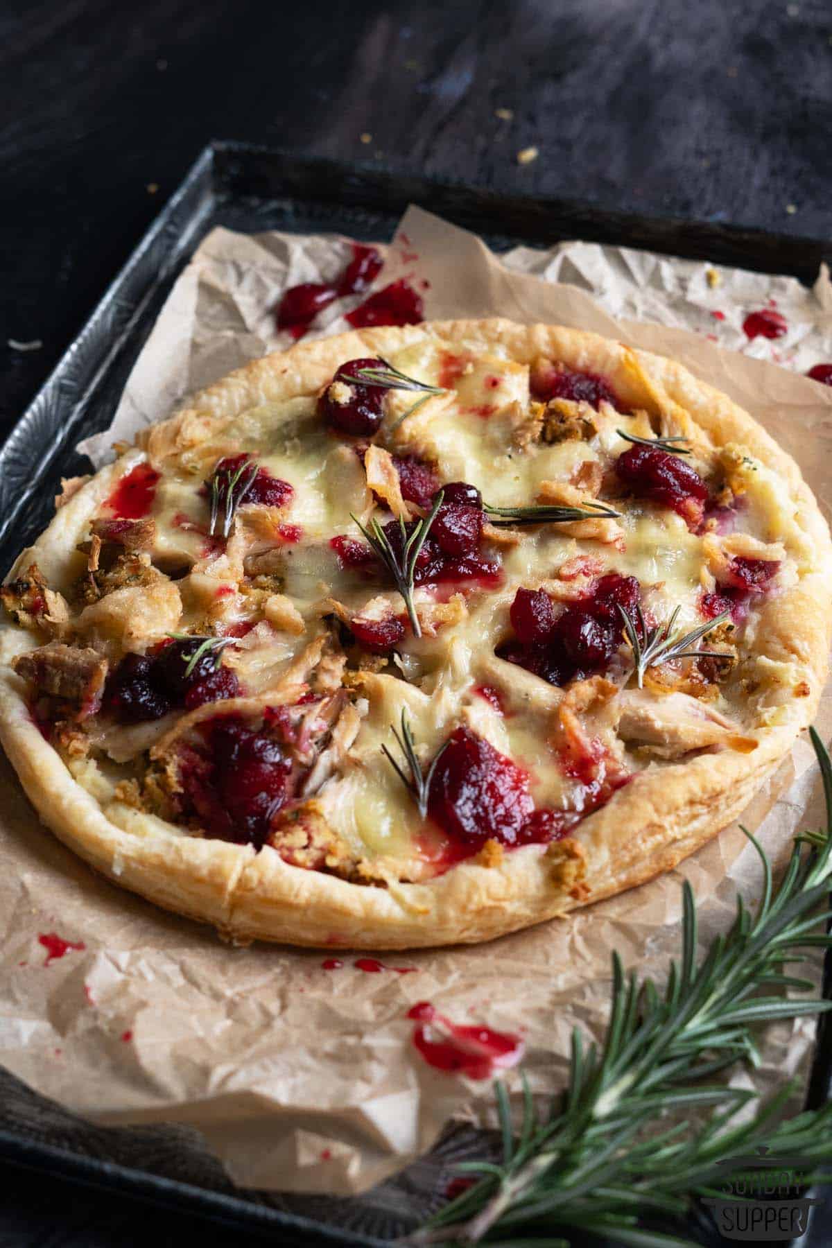 a baked thanksgiving leftover pizza on a baking tray with rosemary