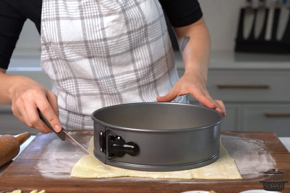 a springform pan placed on top of the puff pastry to cut around