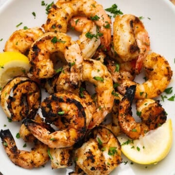 a plate of grilled shrimp with lemon wedges