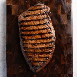 a cooked london broil with sear marks on a cutting board