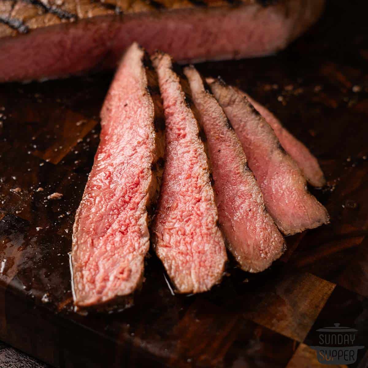 slices of london broil on a cutting board up close