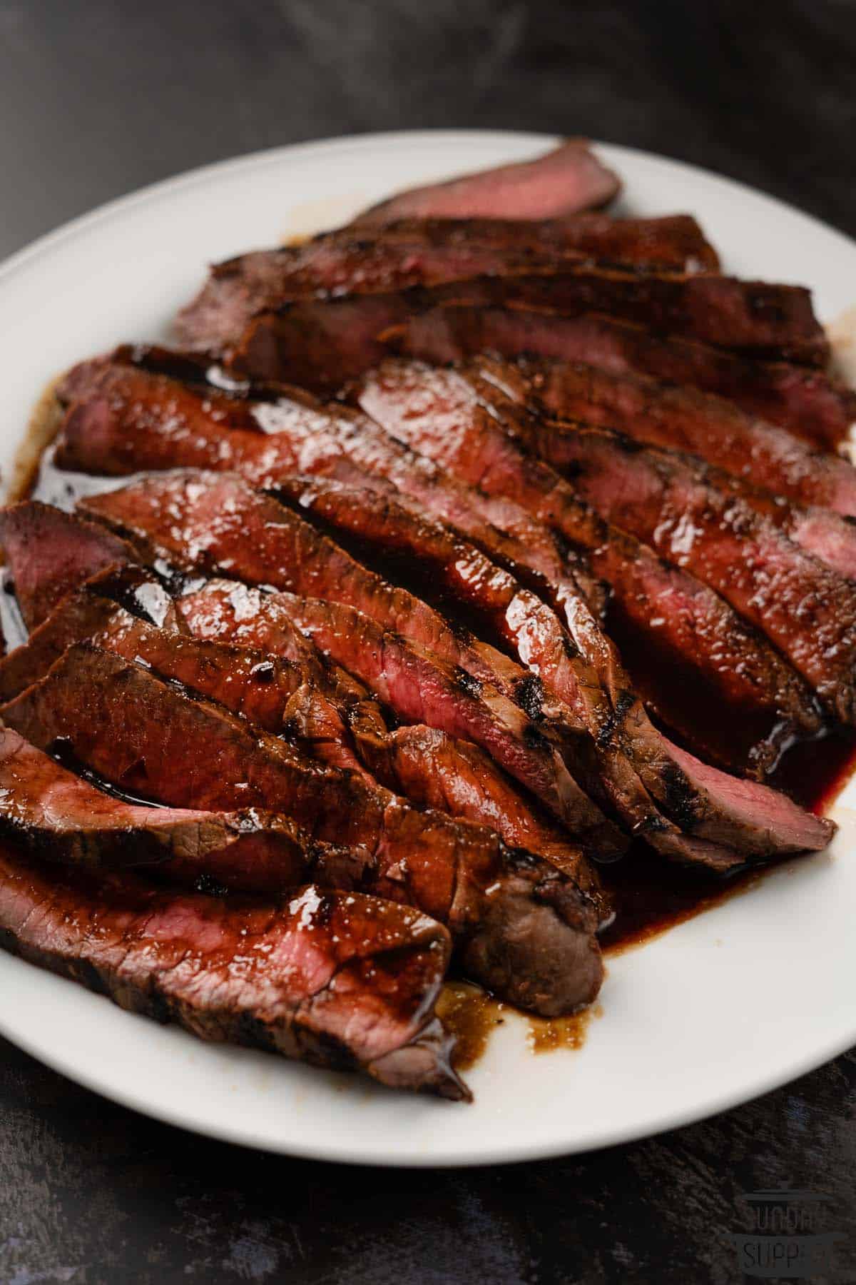 slices of london broil with sauce on a plate