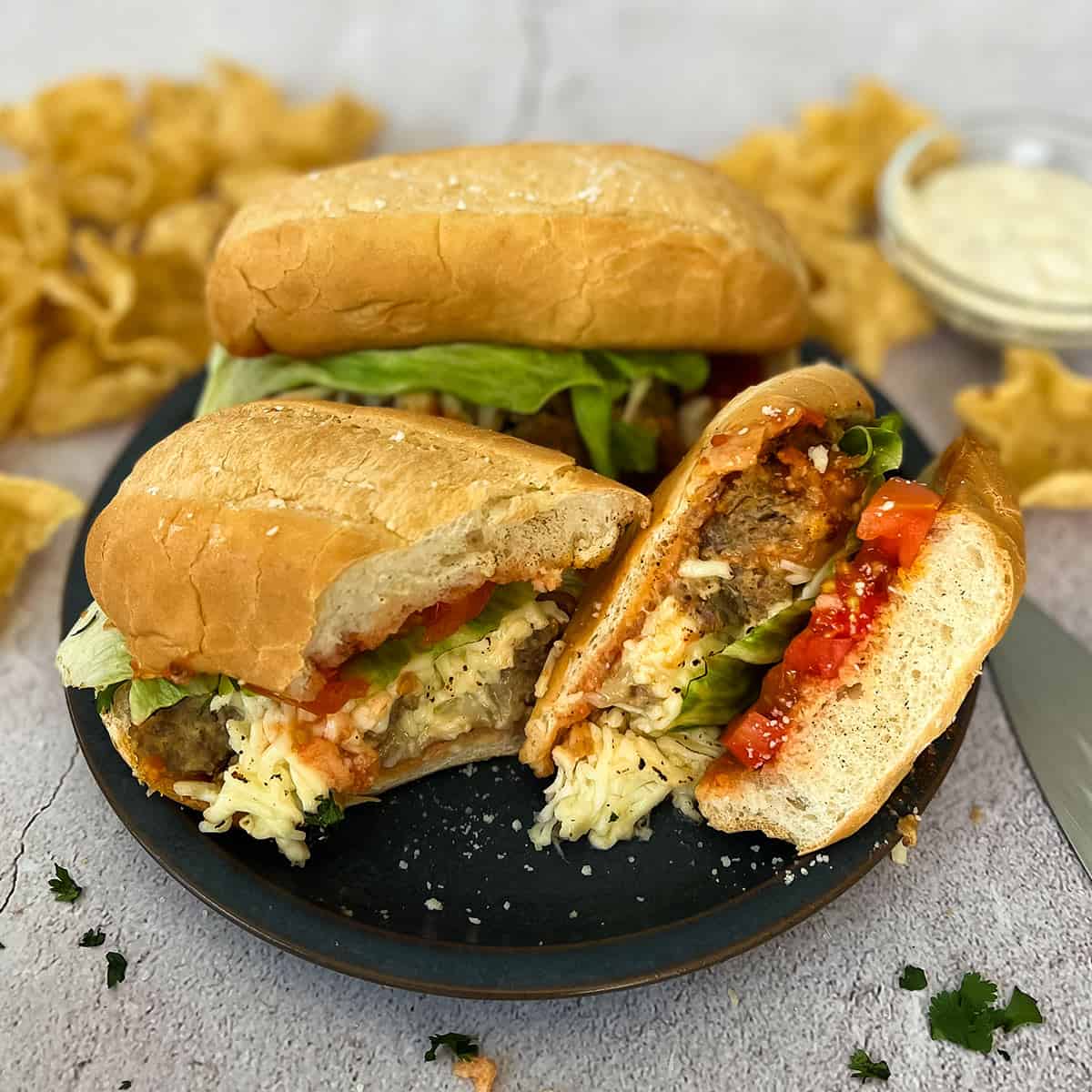 a sliced meatloaf sandwich on a plate with chips and another sandwich