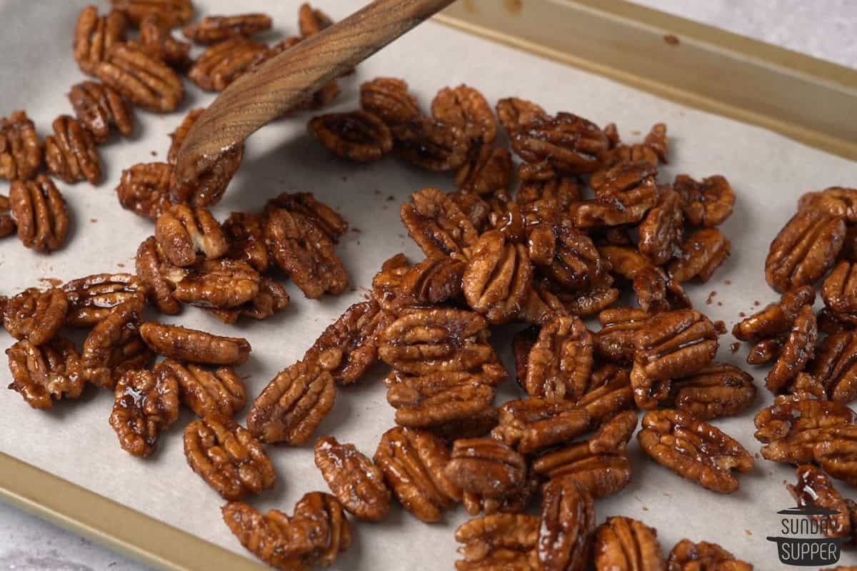 the candied pecans spread out on a baking sheet to dry