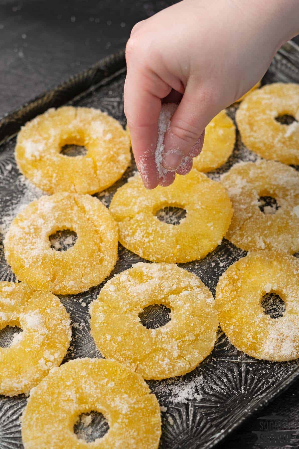 sugar being sprinkled over a tray of candied pineapple