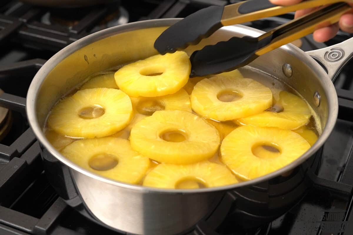 pineapple rings added to the sauce and being flipped