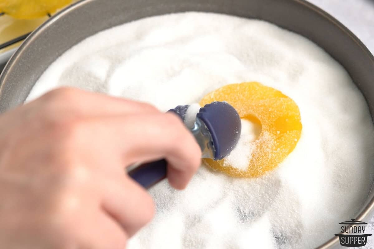 dried pineapple being tossed in sugar