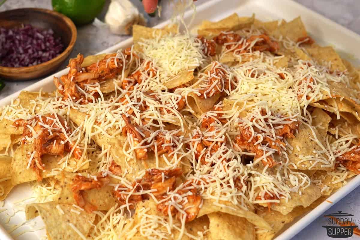 a second layer of chips, cheese, and chicken added to the nachos