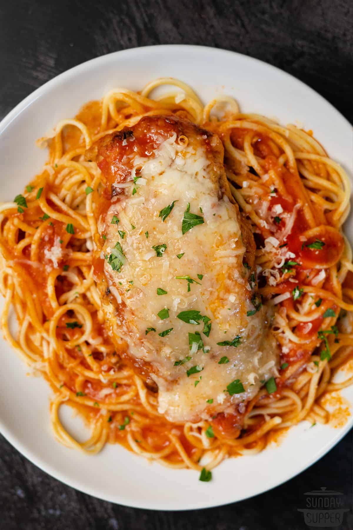 a plate with chicken parmesan on top of spaghetti