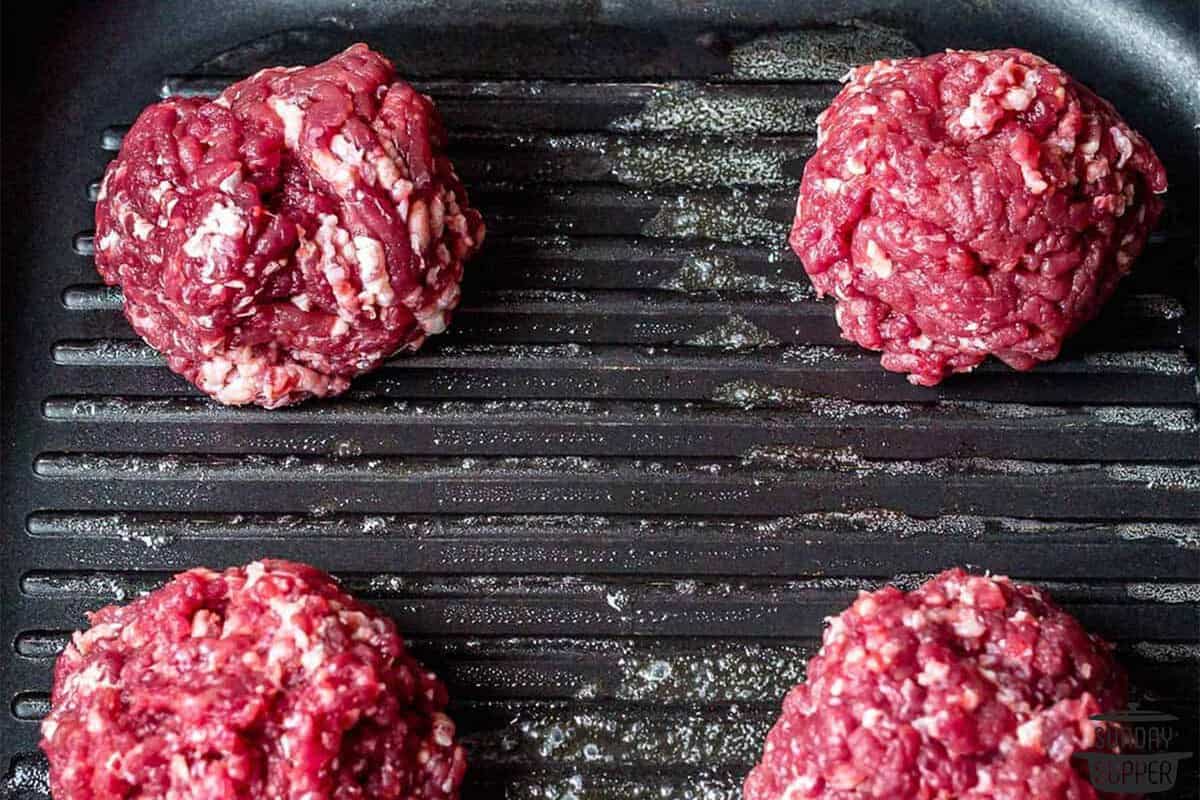 balls of burger meat on a hot griddle