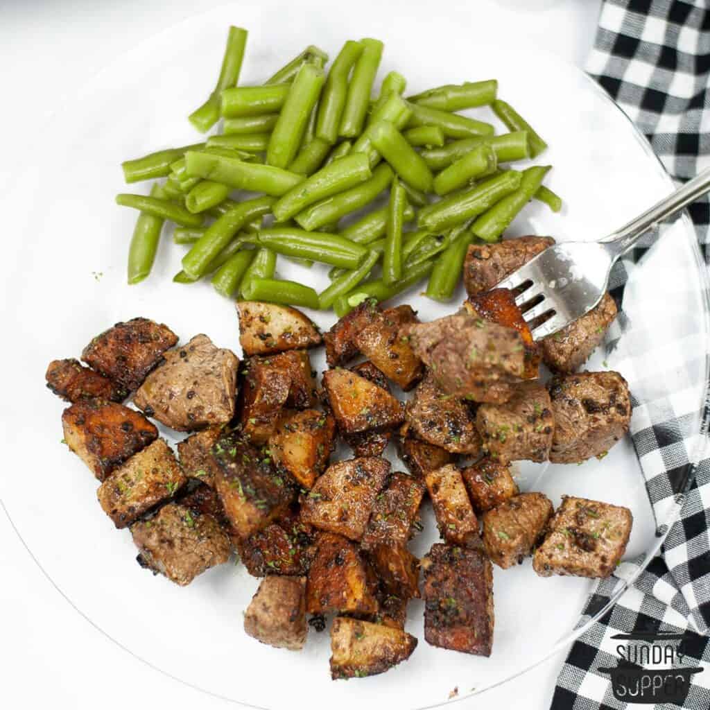 a dinner plate with skillet steak and potatoes and a side of green beans