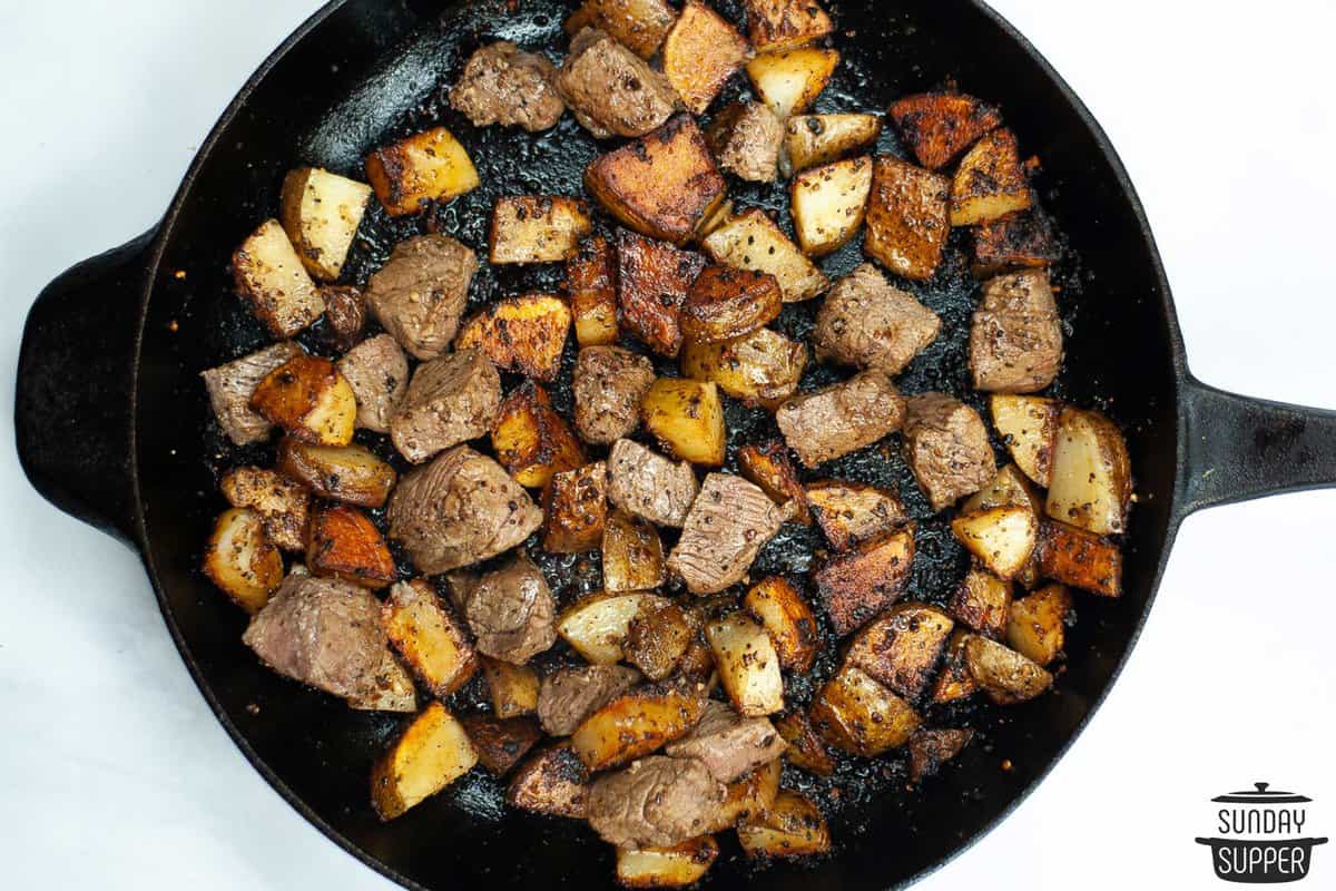 the steak added back to the pan with the potatoes