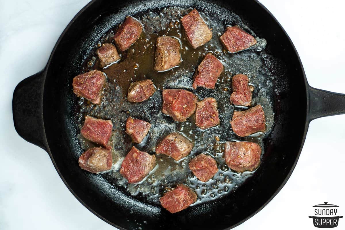 the steak browning in a cast iron pan