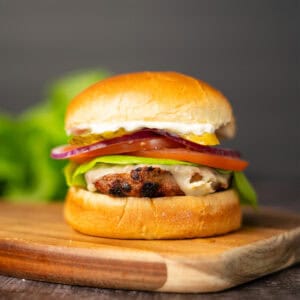 a turkey burger with toppings on a cutting board