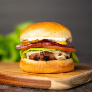 a turkey burger with toppings on a cutting board