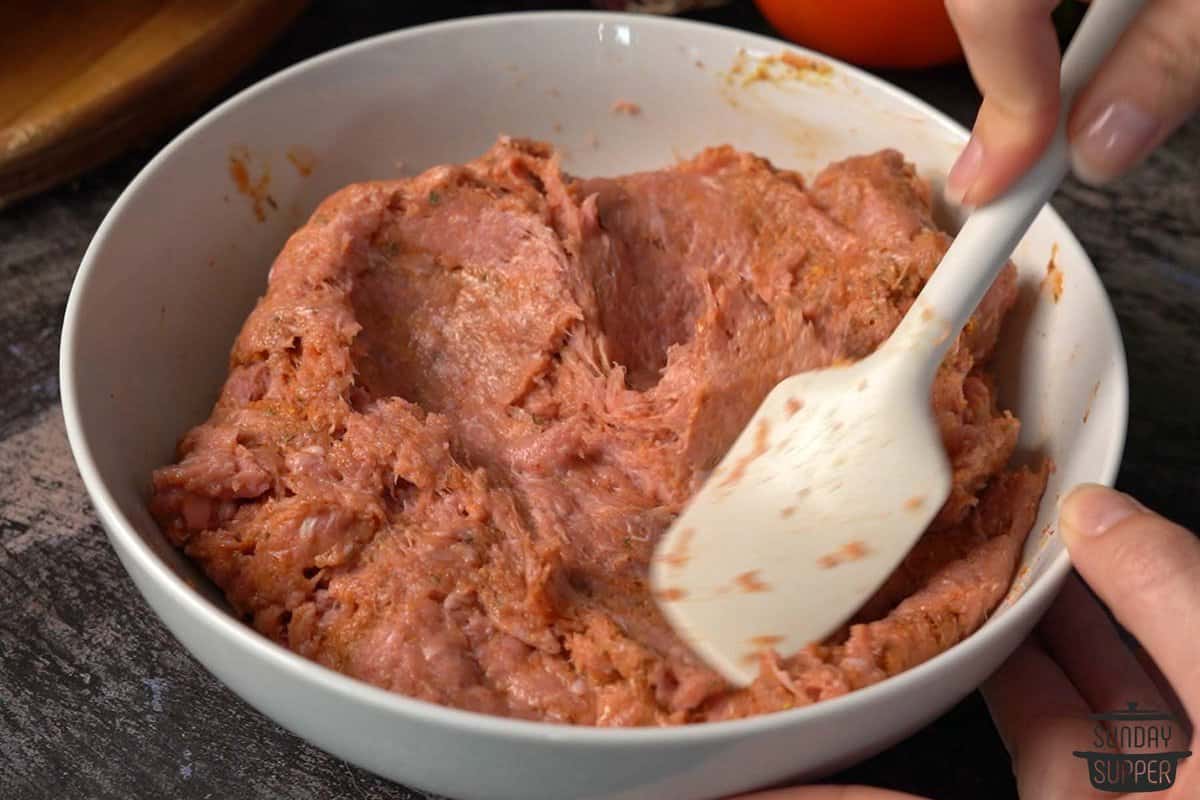 The turkey burger patty mixture being mixed in a bowl