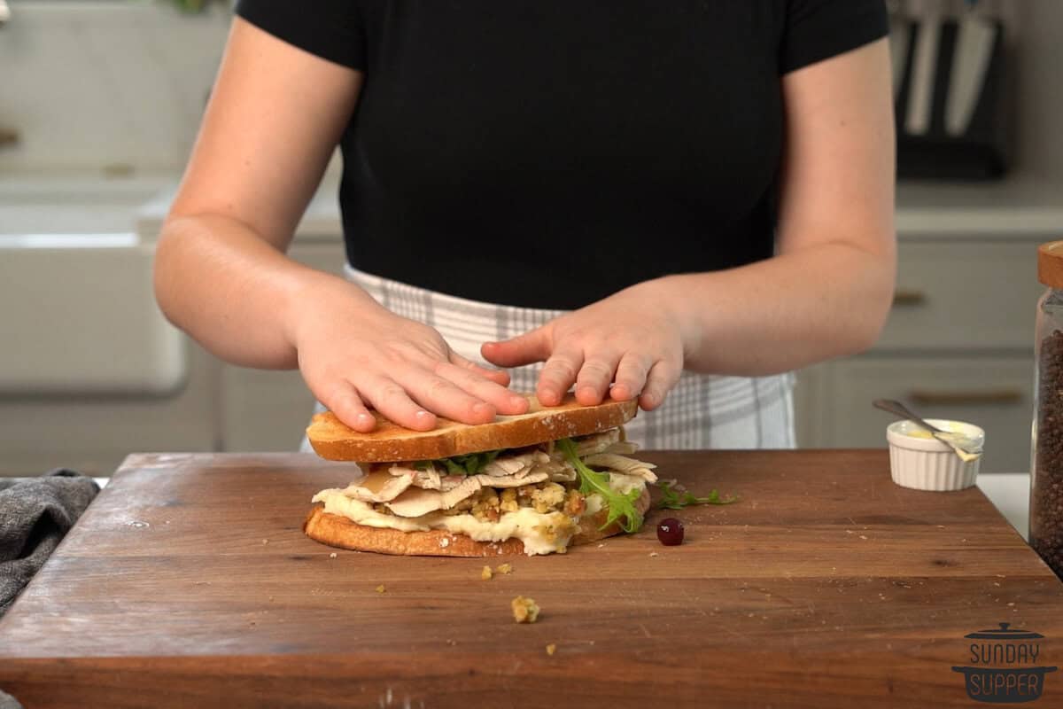 the top slice of bread being put on the sandwich