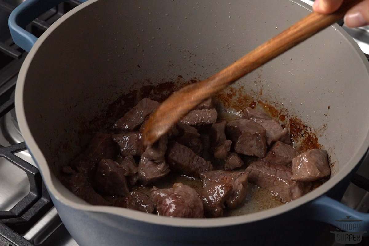 the beef being browned in a pan