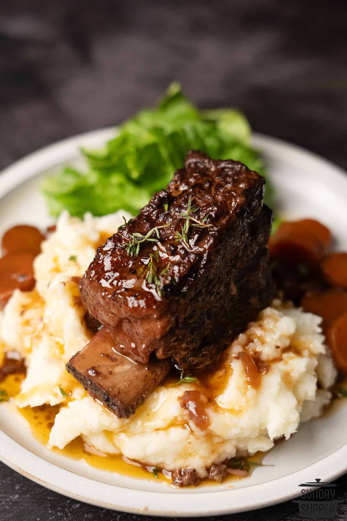 a braised beef short rib on a pile of mashed potatoes