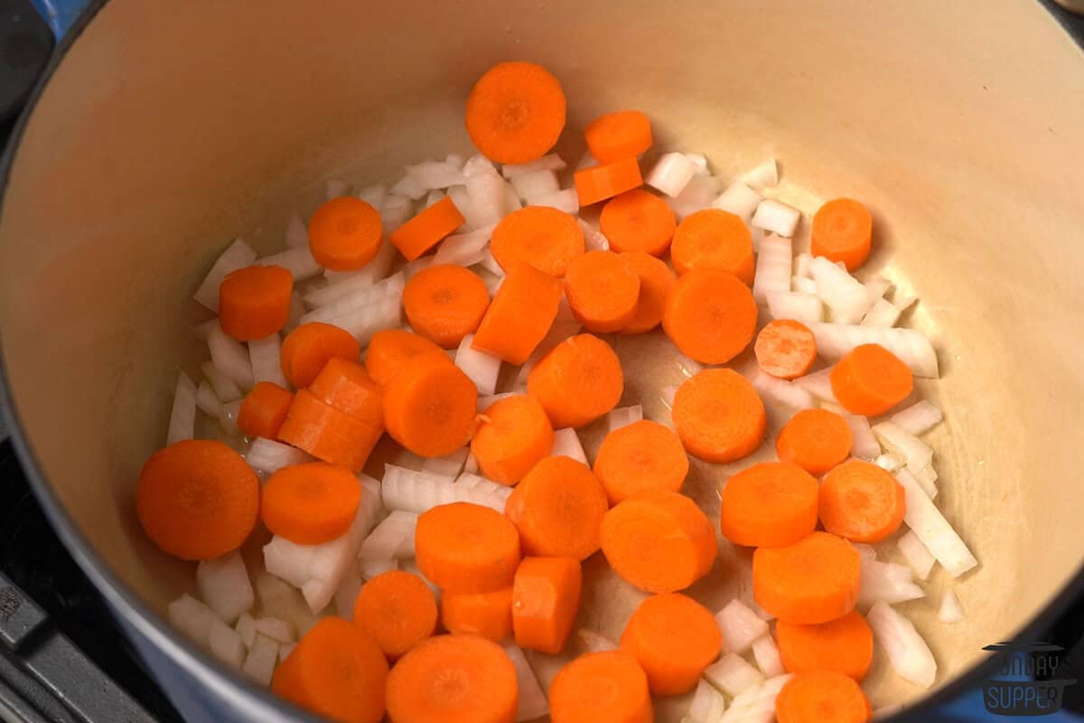 the carrots and onions added to the pot to cook