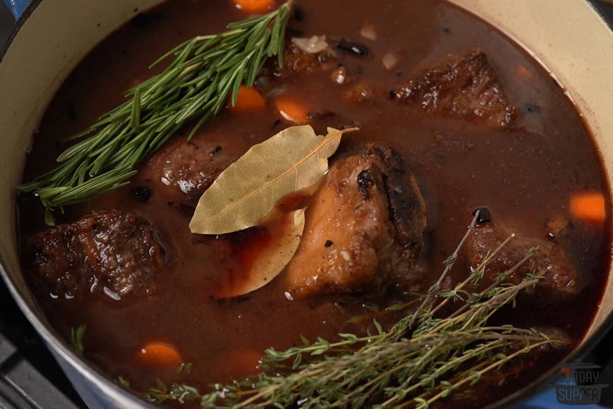 the pot before cooking, with herbs and vegetables added