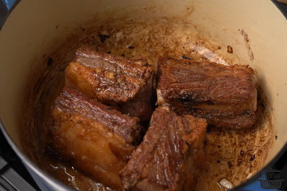 the beef ribs being seared brown in the pot