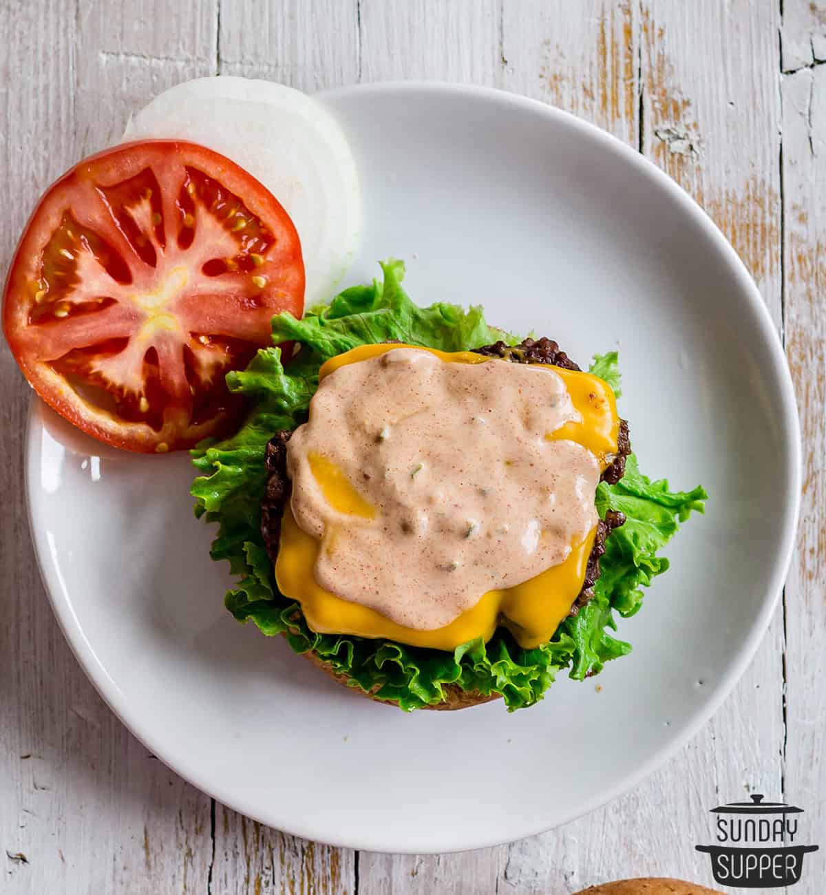 a burger on a plate with burger sauce on top