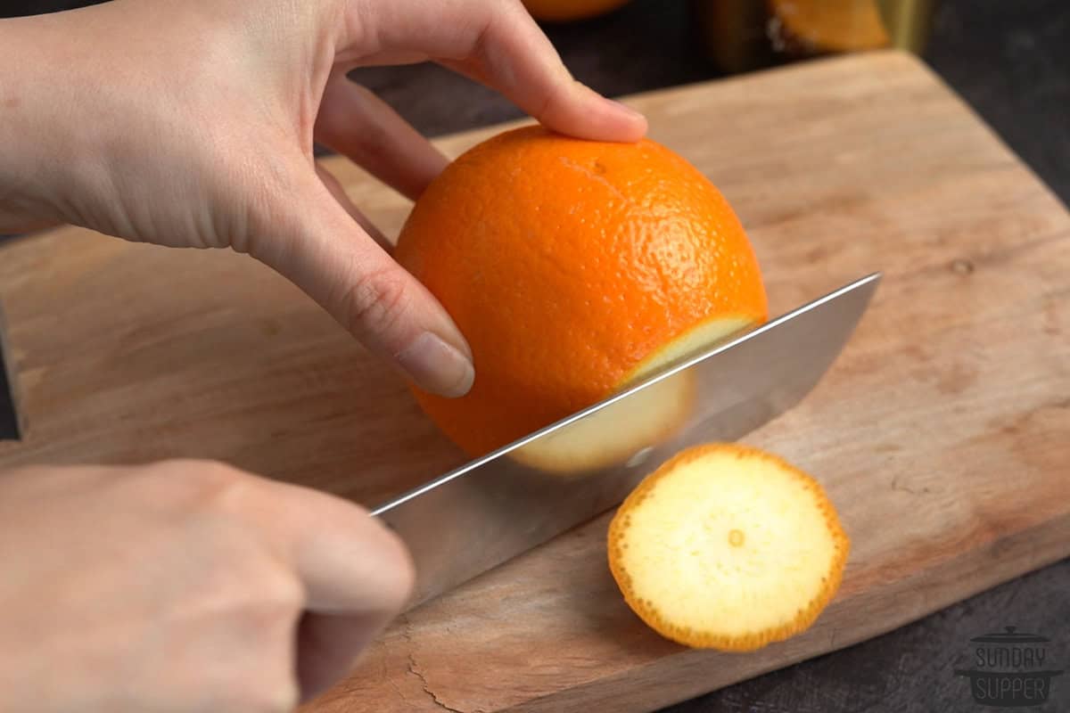 slicing the bottom of an orange off with a knife